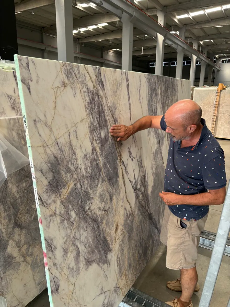 Umut Yeşiltan inspecting a marble slab in the warehouse